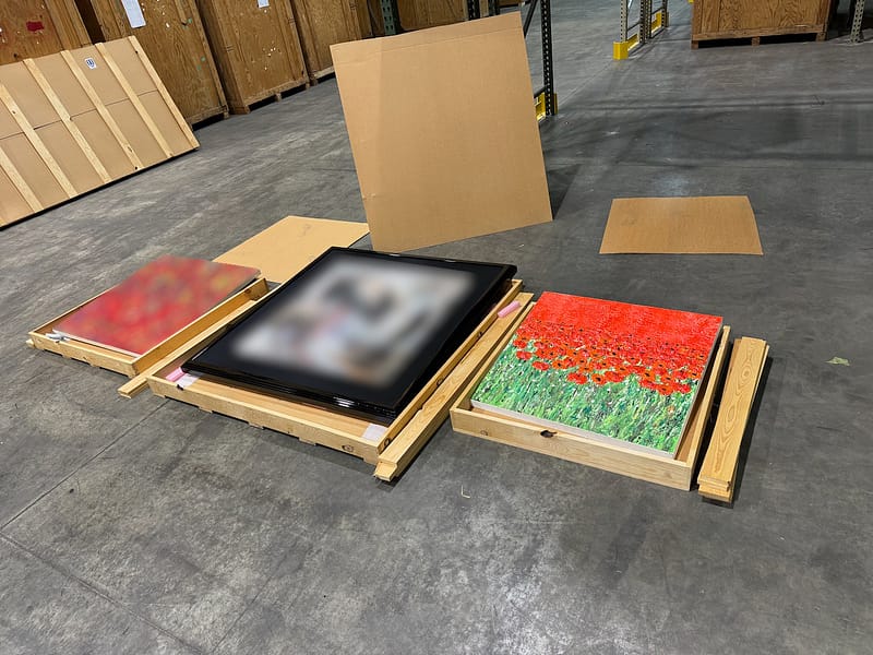 three painting on the ground in crates